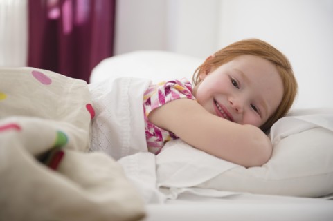 Smiling Caucasian girl laying in bed