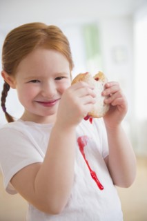 Caucasian girl eating messy jelly donut