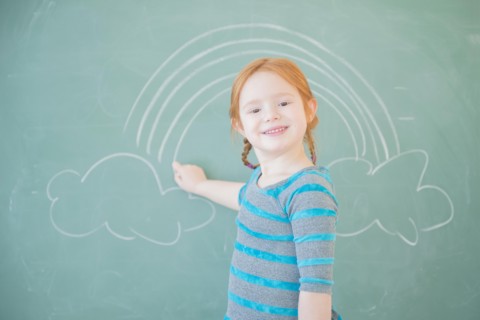 Caucasian girl drawing on chalkboard