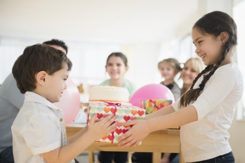Caucasian girl giving brother birthday gift at party