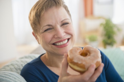 Smiling Caucasian woman eating donut