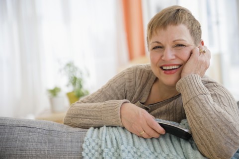 Caucasian woman holding remote control on sofa