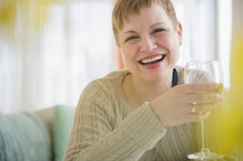 Caucasian woman drinking glass of wine on sofa