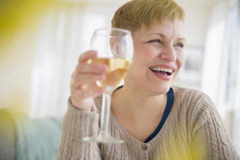 Caucasian woman drinking glass of wine in living room