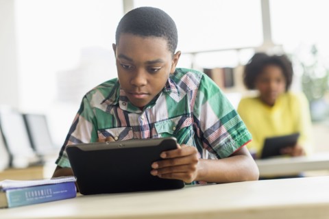 Black student using digital tablet in classroom