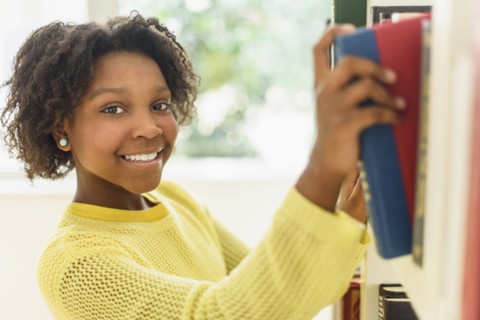 Black student choosing book from library shelf