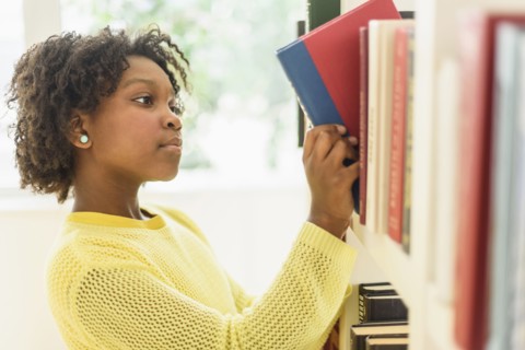 Black student choosing book from library shelf