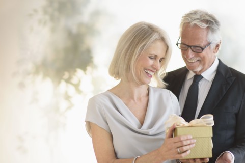 Smiling older Caucasian man giving wife a gift