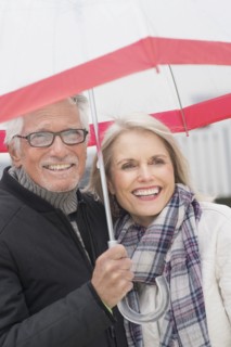 Older Caucasian couple standing under umbrella
