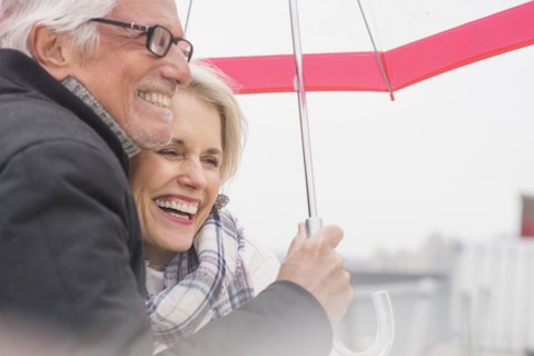 Older Caucasian couple standing under umbrella