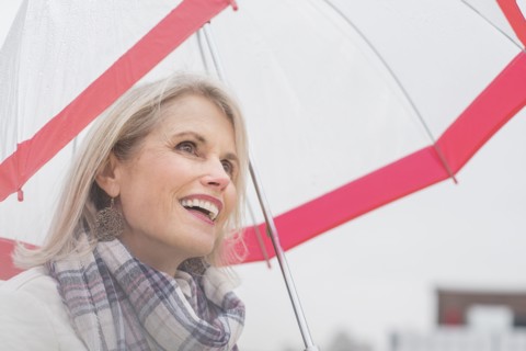 Older Caucasian woman standing under umbrella