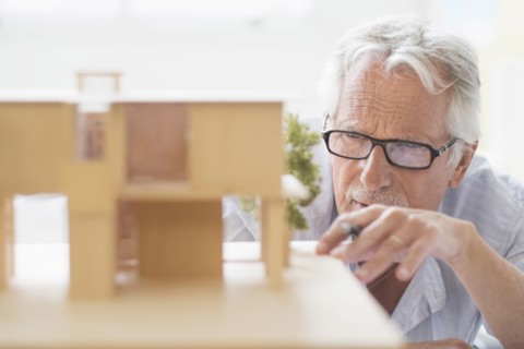 Older Caucasian architect building scale model in office