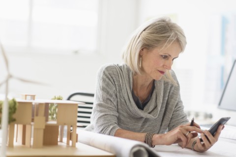 Older Caucasian architect using cell phone in office