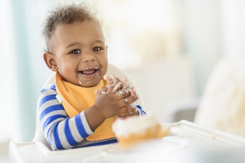 Mixed race baby boy eating in high chair