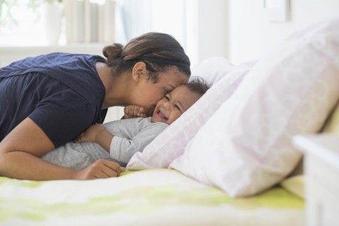 Mixed race mother kissing baby son on bed