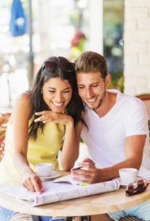 Hispanic couple reading map at cafe