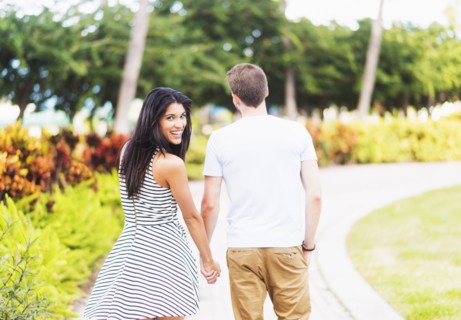 Smiling Hispanic couple walking in park
