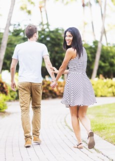 Smiling Hispanic couple walking in park