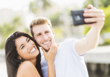Hispanic couple taking selfie outdoors