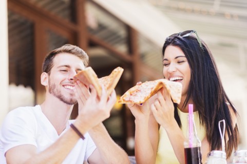 Hispanic couple eating pizza at cafe