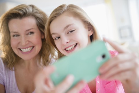 Caucasian mother and daughter taking selfies with cell phone