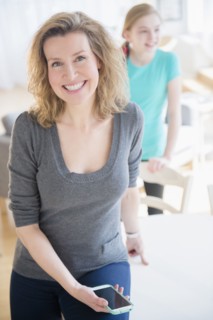 Caucasian woman holding cell phone in dining room
