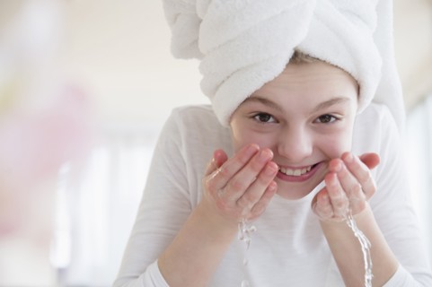 Caucasian girl washing face in bathroom
