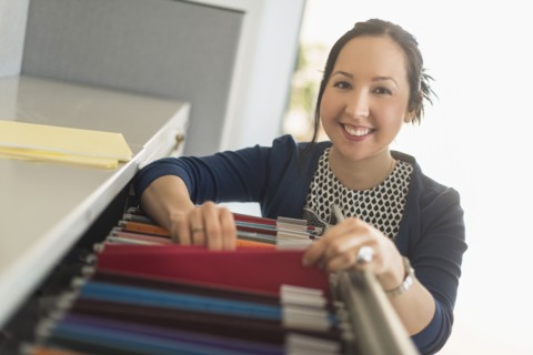 Mixed race businesswoman choosing files in office