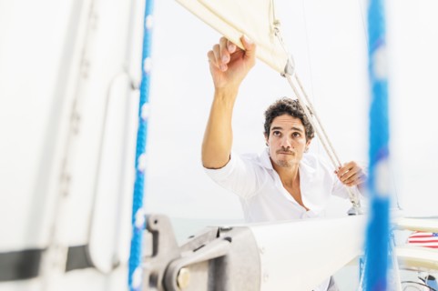 Hispanic man adjusting rigging on sailboat