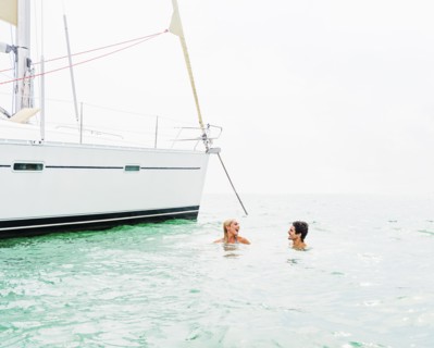 Couple swimming near sailboat
