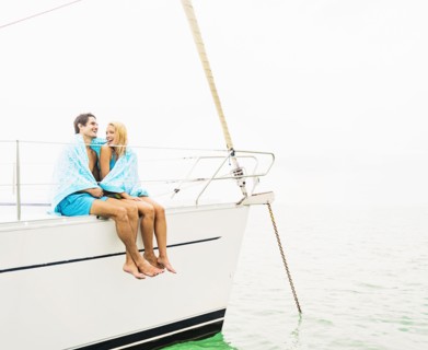 Couple wrapped in towels on deck of sailboat