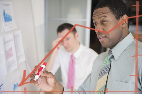 Businessman writing graph on glass wall in office