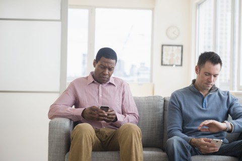 Men with cell phones waiting on sofa