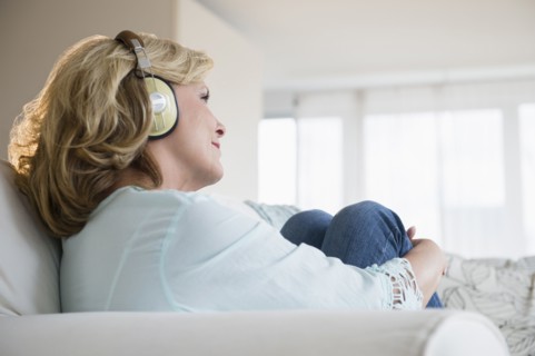 Caucasian woman listening to headphones on sofa