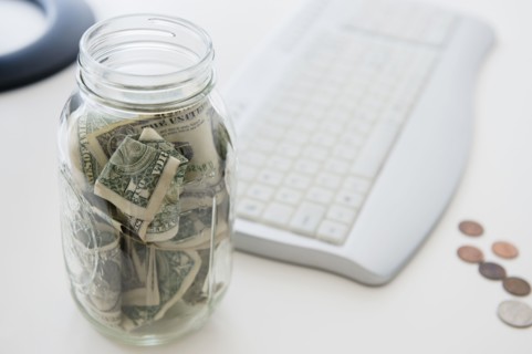 Close up of savings jar near computer keyboard