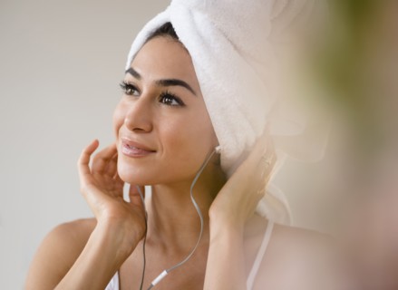 Woman with hair in towel listening to headphones