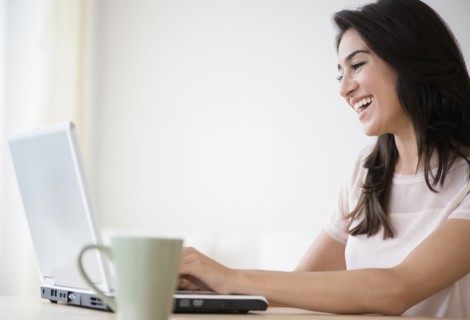 Woman using laptop with cup of coffee