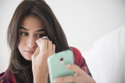 Sad woman crying and using cell phone