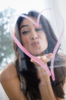 Close up of woman blowing a kiss through heart