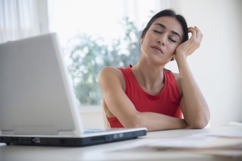 Stressed businesswoman sitting at laptop at desk
