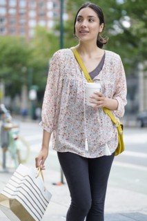 Hispanic woman carrying shopping bag on city sidewalk