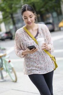 Hispanic woman using cell phone on city sidewalk