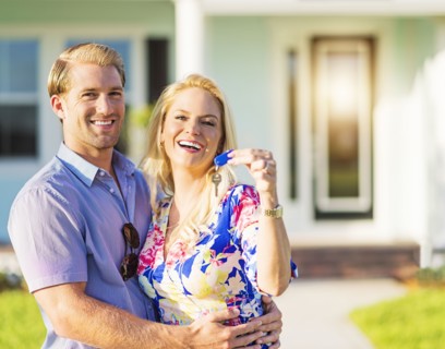 Caucasian couple holding keys outside new home