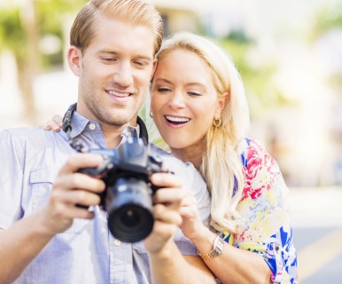 Caucasian couple reviewing digital photographs on camera