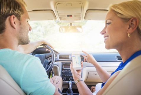 Caucasian couple using cell phone navigation in car