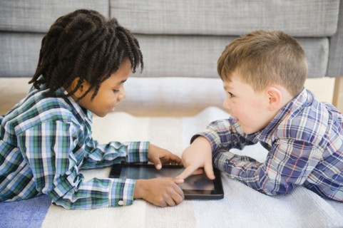 Boys playing with digital tablet on sofa