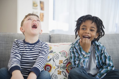 Boys laughing on living room sofa