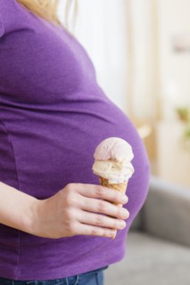 Caucasian pregnant woman holding ice cream cone