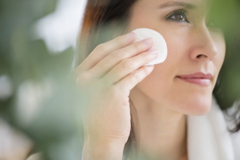 Mixed race woman patting makeup on face