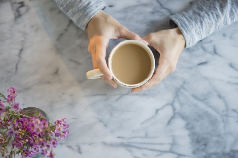 Mixed race woman drinking cup of coffee at table